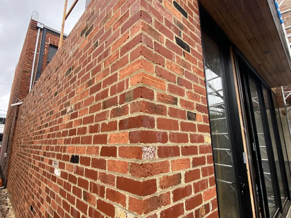Before: new-build red brick elevation with mortar smear