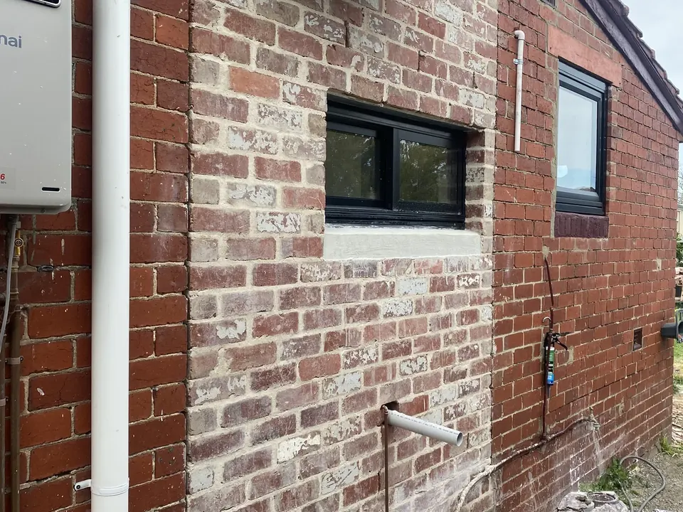 Before: new-build red brick side wall with mortar smear