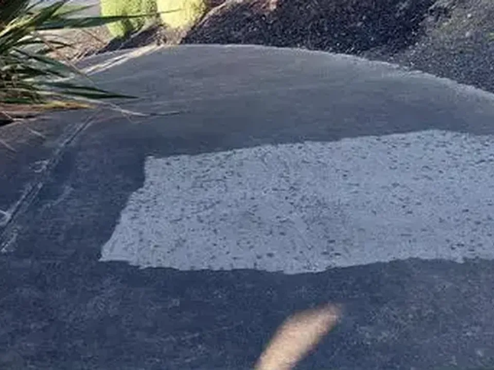 Before: dark driveway with one cleaned test strip